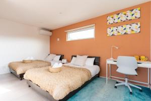 2 Betten in einem Schlafzimmer mit orangefarbener Wand in der Unterkunft Grandioso Onna 7-D - Vacation STAY 86760v in Atsutabaru + 41 Fotos