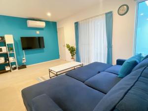 ein Wohnzimmer mit einem blauen Sofa und einem Fernseher in der Unterkunft Grandioso Onna 7-D - Vacation STAY 10596v in Atsutabaru