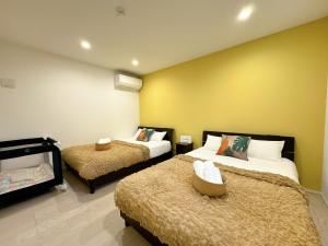 zwei Betten in einem Zimmer mit gelben Wänden in der Unterkunft Grandioso Onna 7-D - Vacation STAY 10596v in Atsutabaru + 43 Fotos