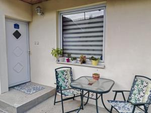 a patio with two chairs and a table and a window at City Apartman in Subotica +2 photos