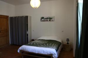 a bedroom with a bed with a green blanket on it at Maison Garde Barriere in Canilhac