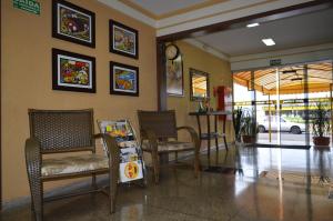a waiting room with chairs and a table and a clock at Hotel Graunas in São Carlos