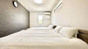 2 Betten in einem kleinen Zimmer mit einer Uhr an der Wand in der Unterkunft Grandioso Onna 7-D - Vacation STAY 17402v in Atsutabaru + 38 Fotos