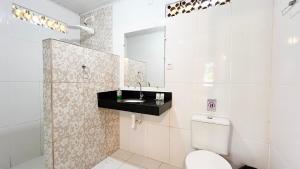 a white bathroom with a sink and a toilet at Pousada Luar das Águas in Ilha de Boipeba