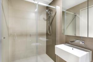 a bathroom with a glass shower and a sink at Studio# on Collins in Melbourne