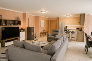 a living room with a large couch and a kitchen at SUNNYHOME Ferienwohnung am Brückelsee in Wackersdorf