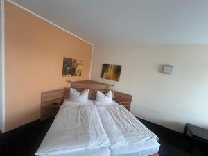 ein Schlafzimmer mit einem Bett mit weißen Laken und Kissen in der Unterkunft Hotel Casa Nostra in Schloß Holte-Stukenbrock + 8 Fotos