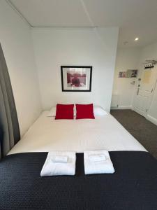 a bedroom with a bed with two red pillows at Reef Lodge in Newquay
