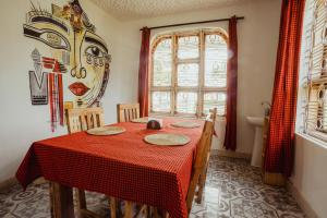 a dining room with a red table with chairs and a window at Meru Villa Arusha in Olmotoni