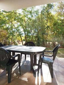 a table and chairs on a patio with trees at Le Chant des Cigales in Azille