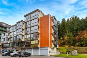 an exterior view of a building with cars parked in a parking lot at Le Cocoon de Belle Hutte sous les sapins in Xonrupt-Longemer