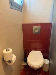 a bathroom with a white toilet and red tiles at Greek Relaxation in Ma‘yan Barukh