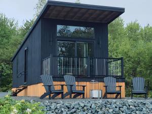 a black tiny house with chairs and a table at Glamping Cabin I Best Bay Views I Near Restaurants in Gouldsboro
