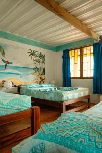 a bedroom with three beds and a painting on the wall at Cabañas Tucan Eco Hotel in Capurganá