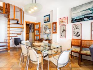 a dining room with a glass table and white chairs at Linda Vista Oasis Penthouse by Hello Homes Sitges in Sitges