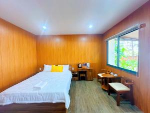 Un dormitorio con una cama y un escritorio y una ventana. en Khu Camping & Homestay Ven Biển, en Ấp Phước Tĩnh