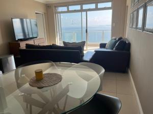 a living room with a glass table and a couch at Oceana Views in Gordonʼs Bay