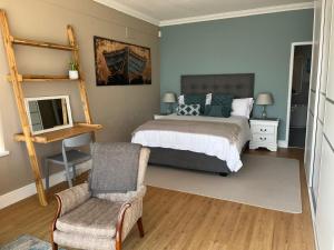 a bedroom with a bed and a chair at Oceana Views in Gordonʼs Bay