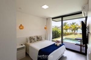ein Schlafzimmer mit einem Bett und Blick auf einen Pool in der Unterkunft Casas em condomínio à beira-mar, OKA Morada dos Milagres - GREs in Barra do Camaragibe