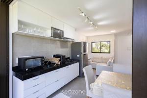 eine Küche mit einem TV und ein Wohnzimmer in der Unterkunft Casas em condomínio à beira-mar, OKA Morada dos Milagres - GREs in Barra do Camaragibe