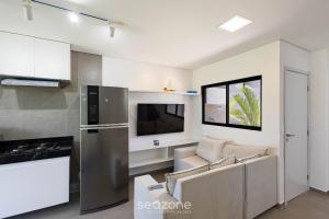 eine Küche und ein Wohnzimmer mit einer Couch und einem Fernseher in der Unterkunft Casas em condomínio à beira-mar, OKA Morada dos Milagres - GREs in Barra do Camaragibe