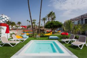 a pool with lounge chairs and a hammock on the grass at Sholeo Lodges Maspalomas in Playa del Ingles