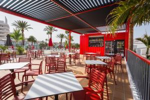 an outdoor patio with tables and chairs and palm trees at Sholeo Lodges Maspalomas in Playa del Ingles