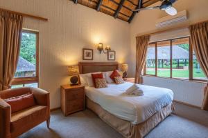 a bedroom with a bed and a chair and a window at Kruger Park Lodge Unit No 237 in Hazyview +40 photos