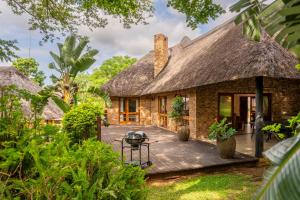 a stone house with a thatched roof and a deck at Kruger Park Lodge Unit No 237 in Hazyview