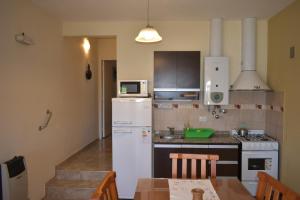 une cuisine avec un réfrigérateur blanc et une table dans l'établissement Aparts Solares, à San Antonio de Arredondo