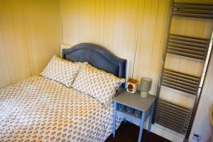 Un dormitorio con una cama azul y una mesa con mesita de noche. en Shepherd Hut in the woods, 