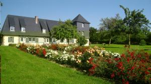 a house with a garden of flowers in front of it at Manoir du Petit Saint-Pierre in Côte de Grâce