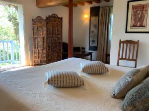a bedroom with a large bed with two pillows on it at Manoir du Petit Saint-Pierre in Côte de Grâce