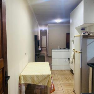 eine kleine Küche mit Tisch und Kühlschrank in der Unterkunft Sobrado com Piscina Oliveira in Mongaguá