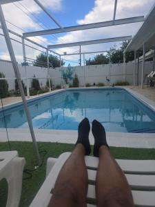 a man with his feet on a bench next to a swimming pool at Healing Minds Home in Miramar