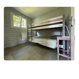 a bedroom with bunk beds with a window and a table at Maison détente in Nonant