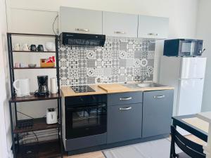 a small kitchen with a stove and a refrigerator at Appartement cosy et lumineux Gravelines centre la gravelinoise 2 in Gravelines