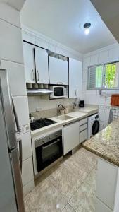 a white kitchen with a sink and a stove at Apartamento na praia in Balneário Camboriú