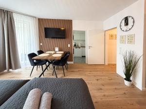 ein Wohnzimmer mit einem Tisch, Stühlen und einer Uhr in der Unterkunft Modernes Studio mit Balkon & Parkplatz, Wifi- K#1 in Osterholz-Scharmbeck + 90 Fotos