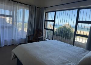 a bedroom with a bed and a large window at Amia in Witsand