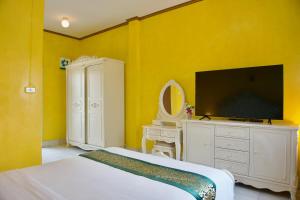 a bedroom with yellow walls and a tv and a bed at จักรพันธ์วอลเลย์ in Ban Bang Toei (1)