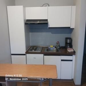 a small kitchen with white cabinets and a sink at Pension Strohm im Lieth Café in Bad Fallingbostel