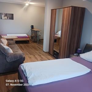 a bedroom with a bed and a couch and a mirror at Pension Strohm im Lieth Café in Bad Fallingbostel