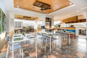 a dining room with tables and chairs and a kitchen at Terrazas Tayrona Travelers Apartamentos y Suites in Santa Marta