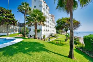 a view of a building with palm trees and the ocean at Beachfront Haven in Mijas Costa
