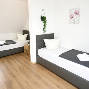 twee bedden in een kamer met witte muren en houten vloeren bij SUNNYHOME Monteurwohnungen und Apartments nahe Regensburg in Nittendorf