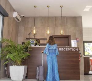 a woman in a blue dress with a suitcase at an airport at Aichti Hotel in Abidjan