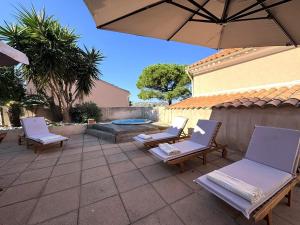 a patio with two chairs and an umbrella at Grande maison avec vue mer et jacuzzi au cœur de Calvi in Calvi