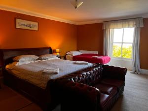 a bedroom with a bed and a leather couch at The Old Farmhouse in Dalkeith