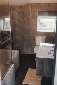 a bathroom with a sink and a toilet and a tub at Charming 2-Bed House by Brookland Stays in Jersey Free Wi-Fi & Parking Included 